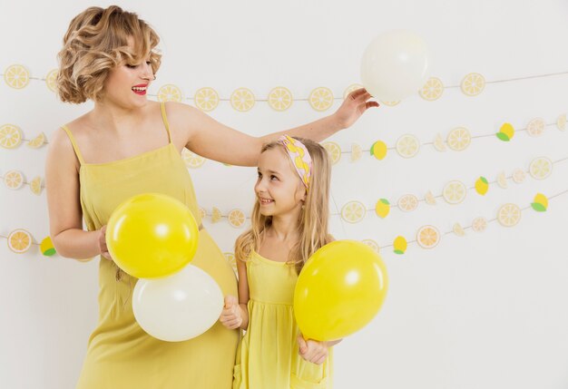 Gratis foto vrouw en meisje poseren met ballonnen