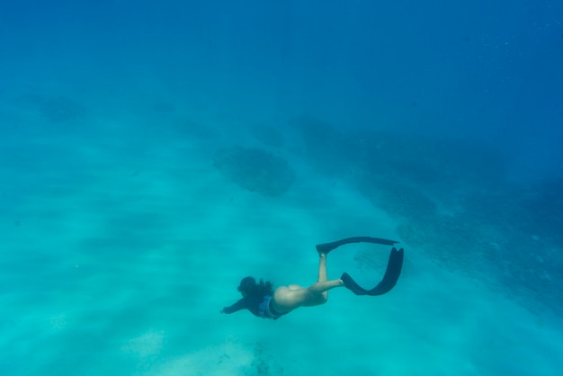 Vrouw freediving met zwemvliezen onder water