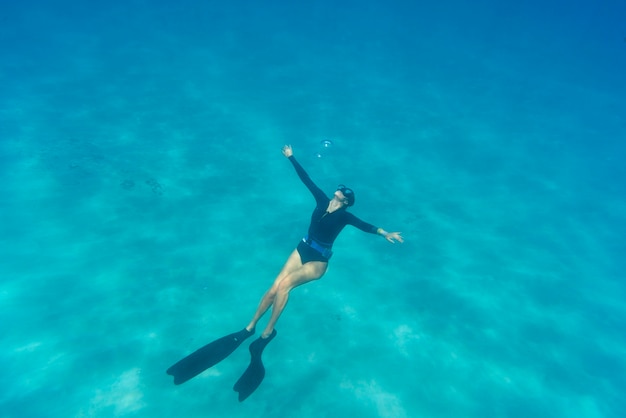 Gratis foto vrouw freediving met zwemvliezen onder water