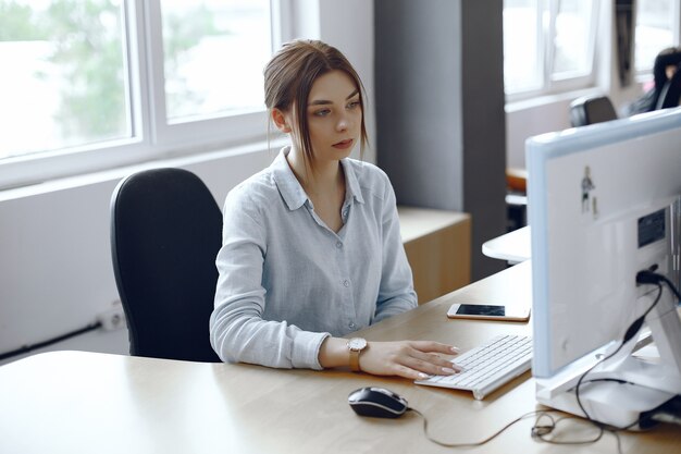 Vrouw gebruikt een computer. Het meisje zit op kantoor. Dame gebruikt het toetsenbord