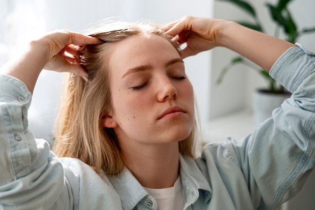 Gratis foto vrouw geeft zichzelf een scalp massage.