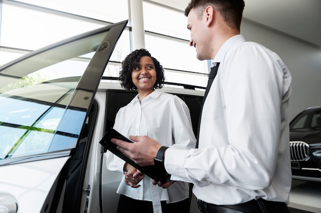 Gratis foto vrouw geniet van haar financiële onafhankelijkheid terwijl ze een auto koopt