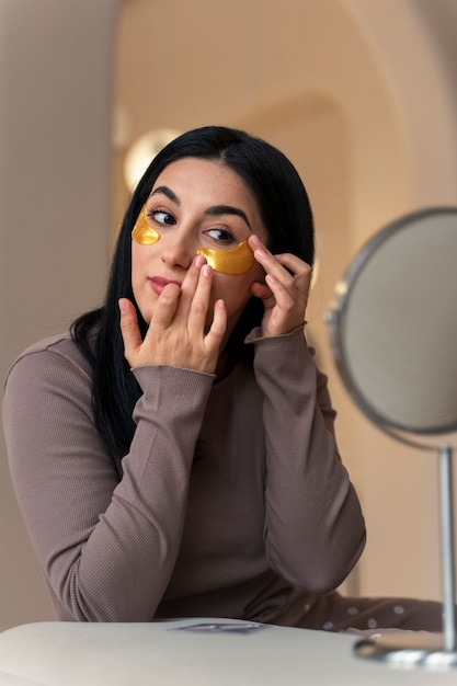 Vrouw geniet van haar schoonheidsroutine met gouden ooglapjes