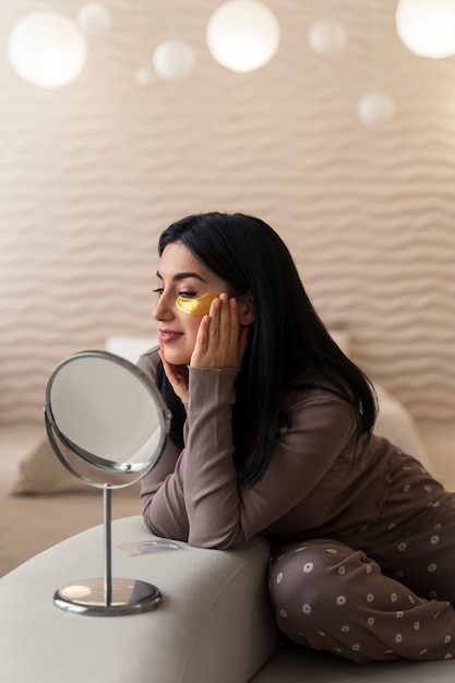 Vrouw geniet van haar schoonheidsroutine met gouden ooglapjes