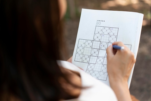 Vrouw geniet zelf van een sudoku-spel op papier