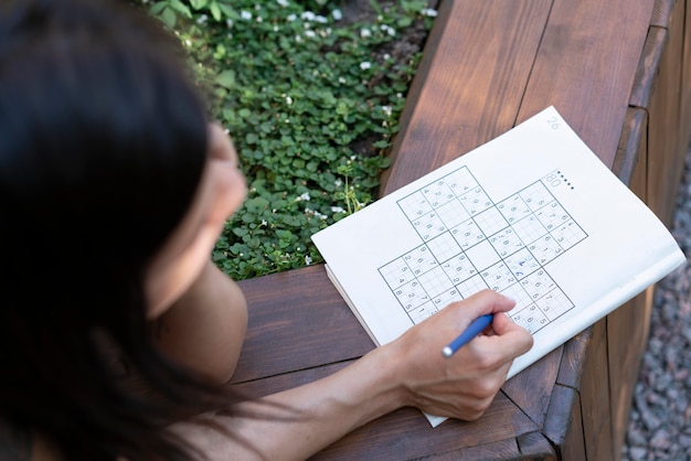 Vrouw geniet zelf van een sudoku-spel op papier Gratis Foto
