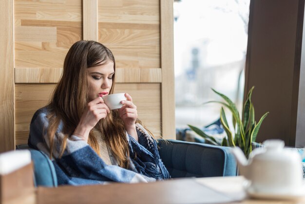 Vrouw genieten van een kopje thee naast het raam