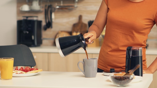 Koffiemolen gebruiken om verse koffie te maken voor het ontbijt. die thuis versgemalen koffie maakt in de keuken voor het ontbijt, drinken, koffie-espresso malen voordat ze naar het werk gaat