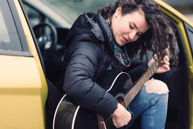 Vrouw gitaarspelen in gele auto