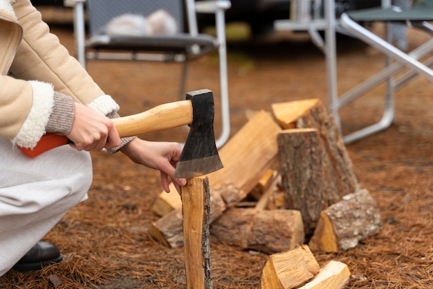 Vrouw hakt hout met een bijl voor een vreugdevuur