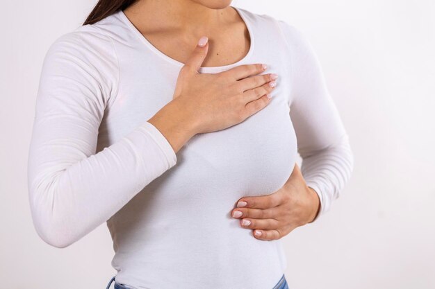 Vrouw hand controleren knobbels op haar borst voor tekenen van borstkanker op grijze achtergrond Gezondheidszorg concept close-up van de hand van een vrouw op de borst met kanker symptoom