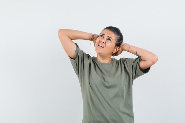 vrouw hand in hand achter hoofd in t-shirt en op zoek verward