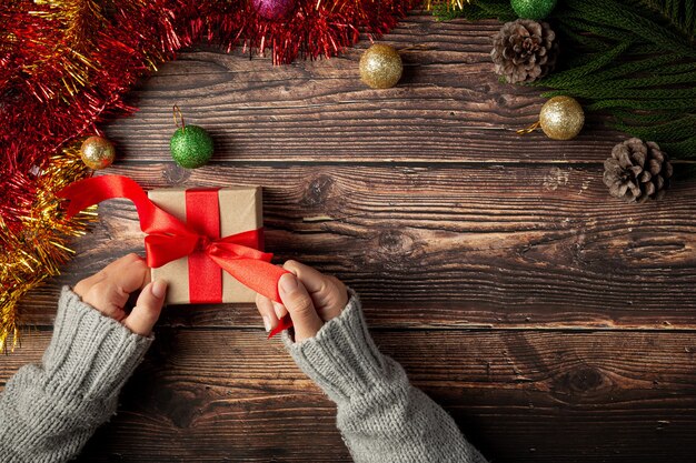 Vrouw hand met een geschenkdoos met rood lint op houten vloer