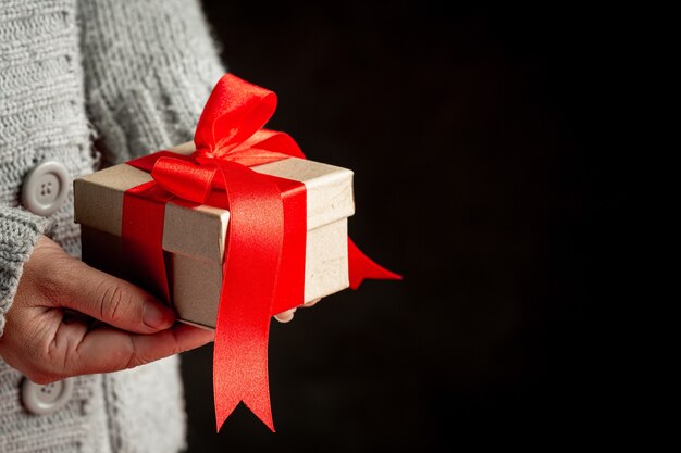 Vrouw hand met een geschenkdoos met rood lint