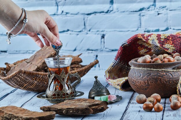 Vrouw hand met een lepel thee en diverse snoepjes op blauwe houten tafel