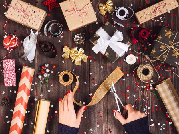 Vrouw hand met jute lint met een schaar voor het snijden en de verpakking van de doos van de gift van Kerstmis