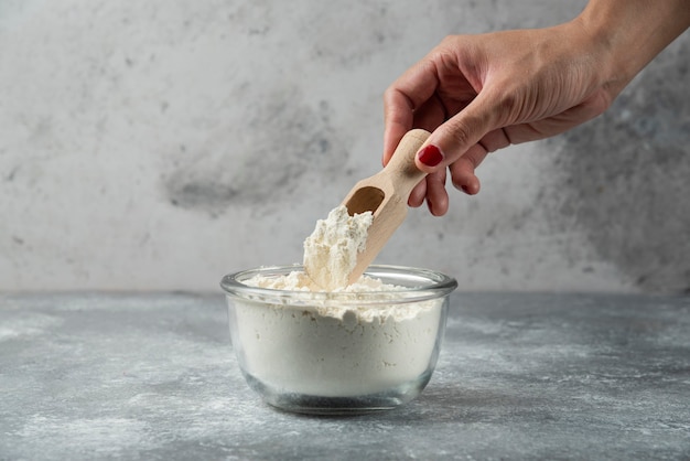 Vrouw hand met lepel bovenop bloem kom.