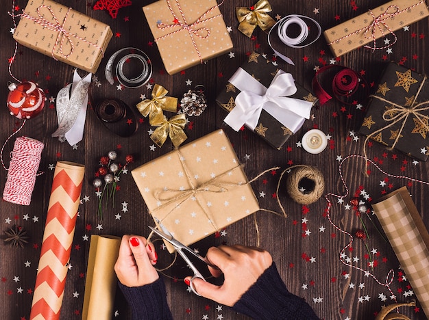 Vrouw hand met touw touw met een schaar voor het snijden en de verpakking van de doos van de gift van Kerstmis