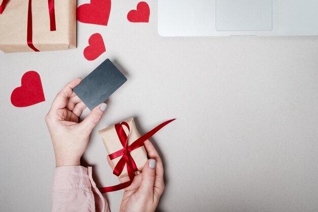 Vrouw handen met creditcard en laptop geschenkdoos met hart en koffie op witte achtergrond Valentine dag online winkelen concept vakantie achtergrond Bovenaanzicht