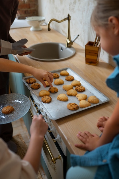 Gratis foto vrouw helpt kinderen koekjes bakken onder een hoge hoek