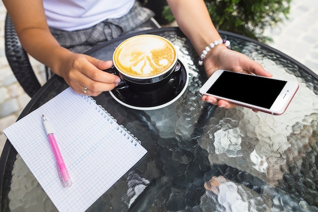 Vrouw het drinken smartphone van de koffieholding