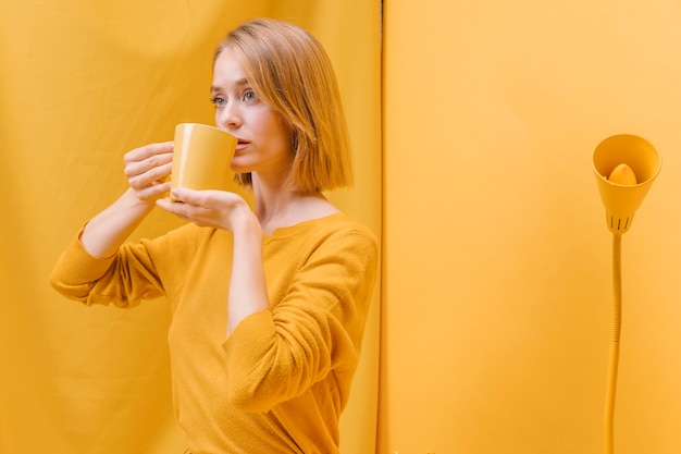 Vrouw het drinken van mok in een gele scène