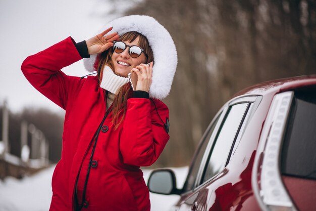 Vrouw het gelukkige spreken op de telefoon buiten door auto in de winter