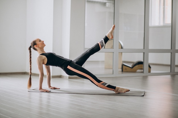 Vrouw het praktizeren yoga in de gymnastiek op een mat