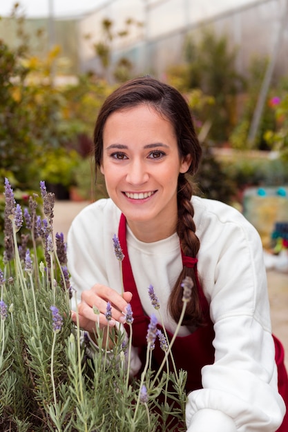 Gratis foto vrouw het stellen dichtbij lavendel in serre