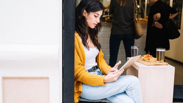 Gratis foto vrouw het tikken het schermzitting van de tablet in koffie