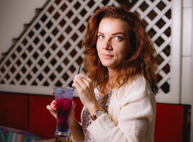 Vrouw houdt cocktailglas met zwarte plastic stropijp