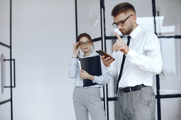 Vrouw houdt een map. Zakelijke partners op een zakelijke bijeenkomst. Man maakt gebruik van de telefoon. Mensen met een bril