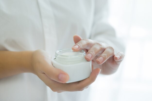 vrouw houdt een pot met een cosmetische crème in haar handen