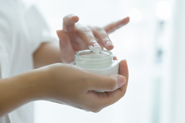 vrouw houdt een pot met een cosmetische crème in haar handen