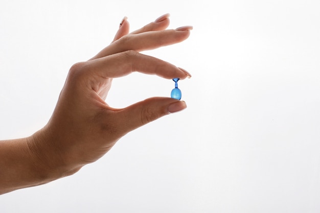 Vrouw houdt in haar hand een capsule met vitaminen of olie