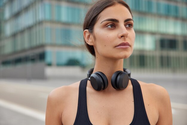 Vrouw in activewear geniet van een actieve, gezonde levensstijl, luistert naar motiverende muziek terwijl ze traint en maakt gebruik van accessoire poses buitenshuis