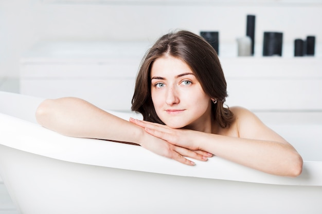 Vrouw in badkuip met handen aan kant