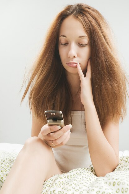 Vrouw in bed met telefoon