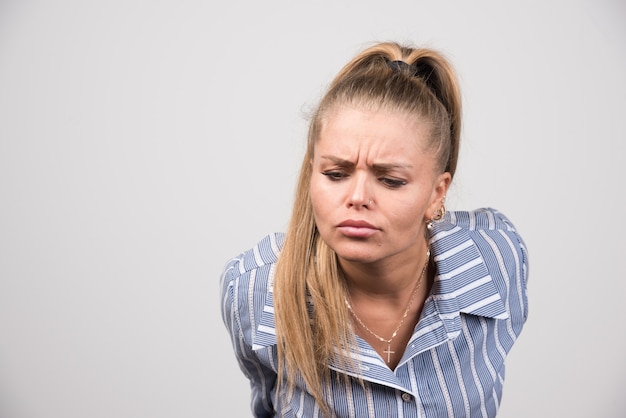 Vrouw in blauwe trui poseren op grijze muur.