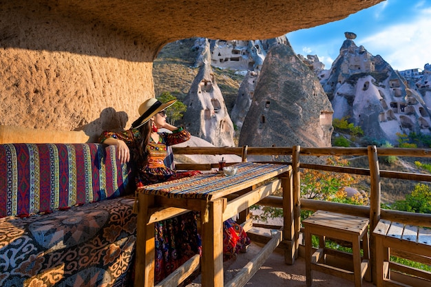 Vrouw in Boheemse jurk zittend op traditionele grotwoning in Cappadocië, Turkije.