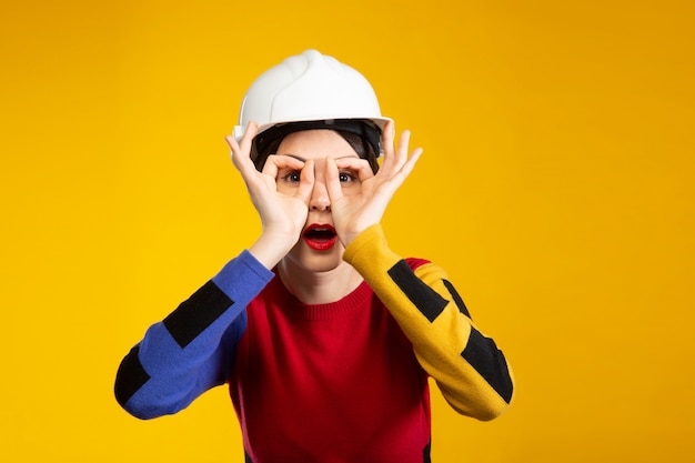 Vrouw in bouw helm toont bril met vingers