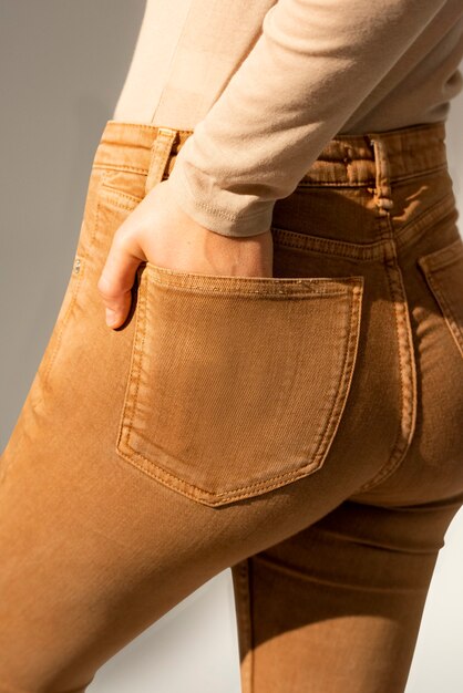 Vrouw in bruine spijkerbroek met hand in zak
