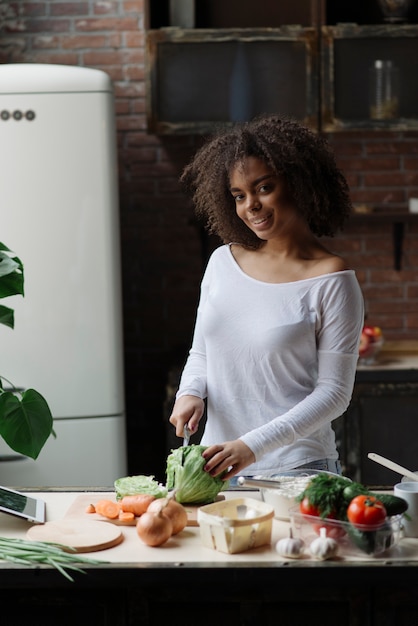 Vrouw in de groente van de keuken snijden