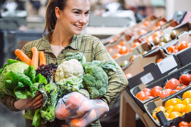 Vrouw in de supermarkt. Mooie jonge vrouw die in een supermarkt winkelt en verse biologische groenten koopt