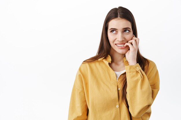 Vrouw in de verleiding om iets te proberen, wil iets lekkers eten, online bestellen, vingernagels bijten en met verleiding en verlangen naar het logo van de linkerbovenhoek kijken, witte achtergrond