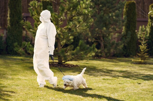 Vrouw in een beschermend pak wandelen met een hond