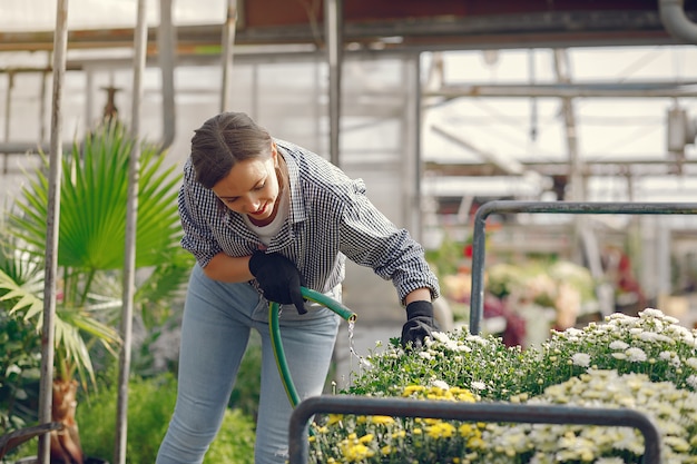 Vrouw in een blauw shirt giet bloempotten