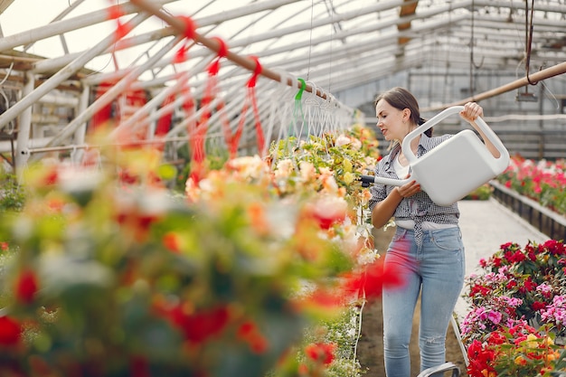 Vrouw in een blauw shirt giet bloempotten