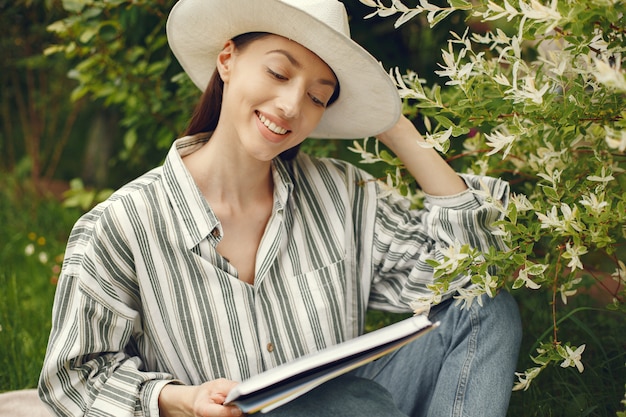 Vrouw in een hoed met een boek in een tuin