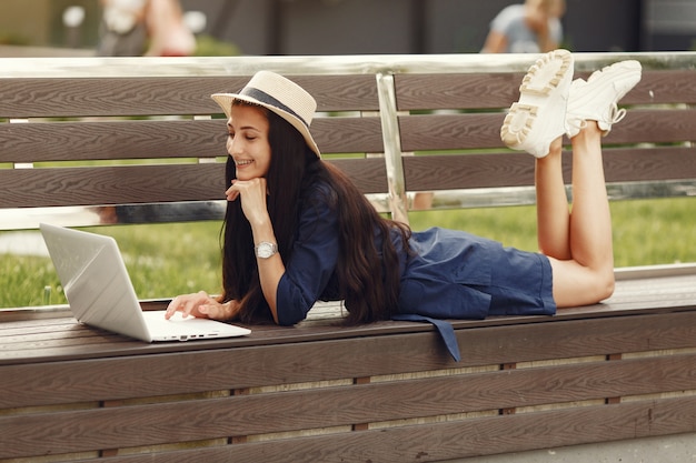 Vrouw in een lentestad. Dame met een laptop. Meisje zittend op een bankje.